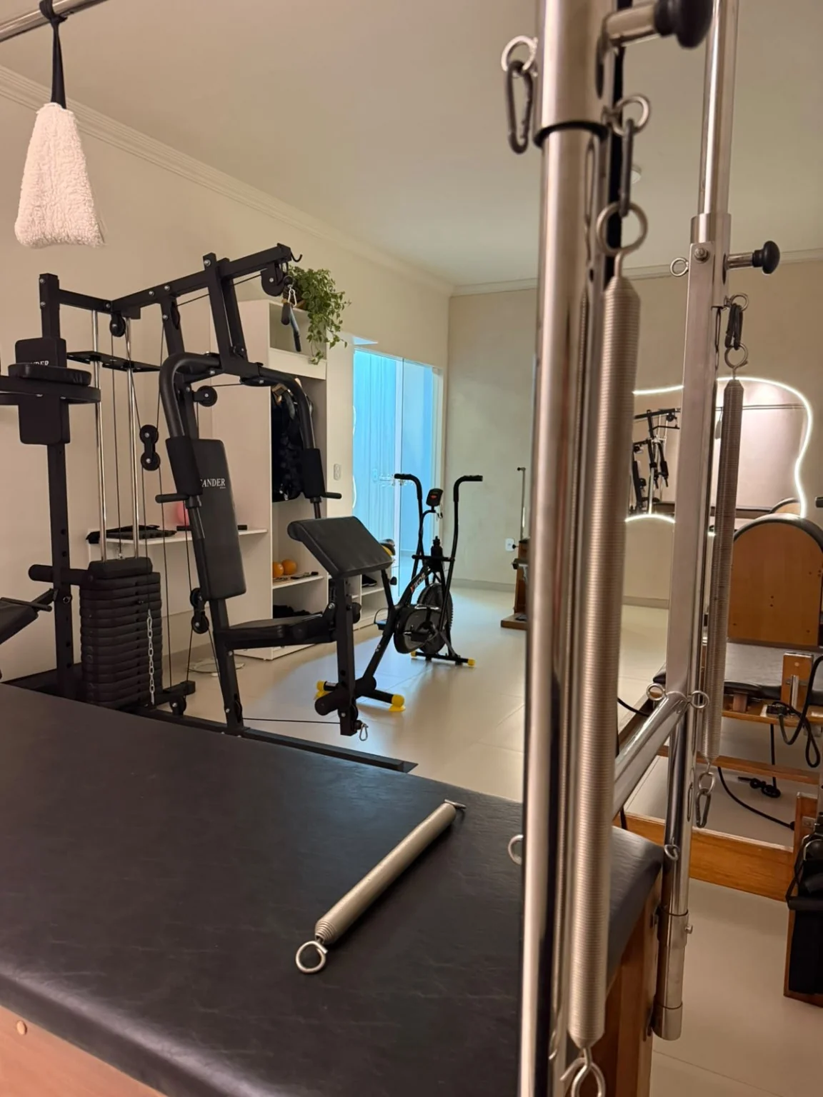 Detalhe do equipamento de Pilates em primeiro plano no ambiente da clínica.